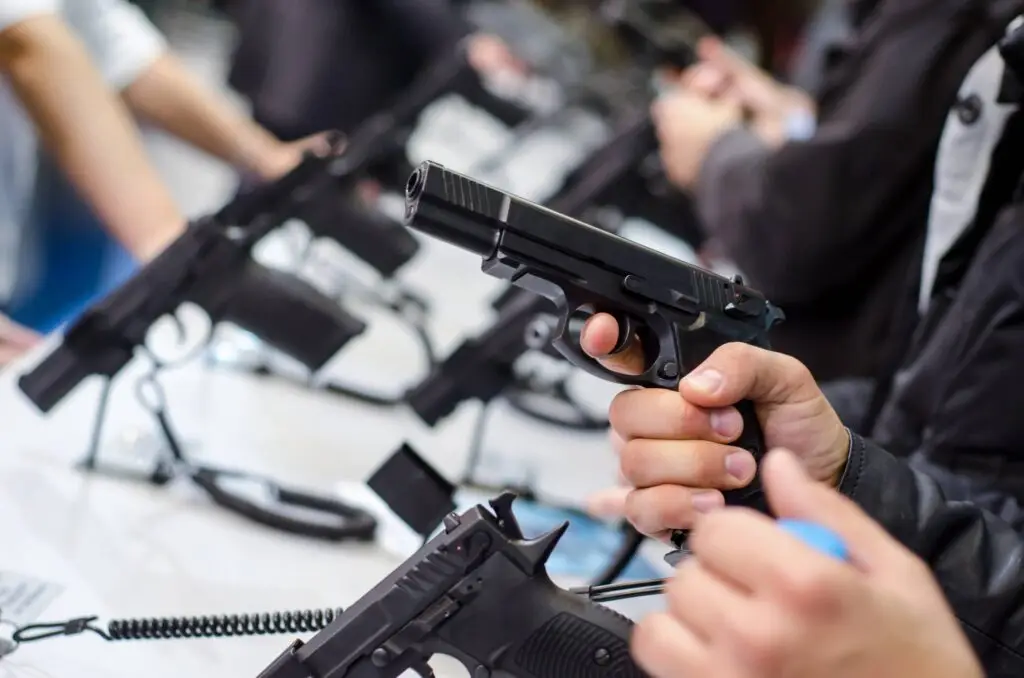 A person holds a black handgun at a gun display.