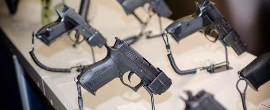 Black handguns are displayed on display table.
